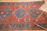 Antique Caucasian rug's geometric border and stylized crab motifs in cherry red, sky blue, and mallard green.