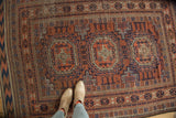 Geometric medallions and layered borders of a Persian antique Belouch rug in rich copper tones and navy.