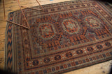 Antique tribal Belouch rug corner, detailing layered geometric borders in copper, navy, and ivory.