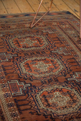 Geometric design and pile texture in copper bronze, navy blue, and ivory from an antique Belouch rug.