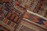 Antique Belouch rug's folded corner, revealing chevron kilim and geometric copper, navy patterns.