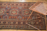 Antique Belouch rug's intricate geometric borders and plain weave end in copper, navy, and brown.
