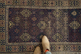 Antique Belouch rug, geometric guls in navy, madder red, ivory lattice, showcasing pile wear.