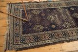 Early 20th century Persian Belouch rug, geometric guls in navy, red, and sand, visible wear and tatter.