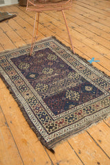 Repeating geometric guls in navy, madder red, ivory, and tattered fringe on antique Belouch.