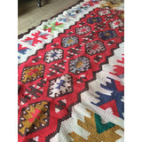 Detail of the vintage Turkish Kilim rug's geometric red, white, and multi-color medallion patterns.