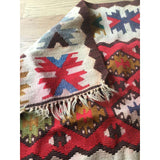 Tattered fringe and geometric patterns on a vintage Turkish Kilim flatweave.