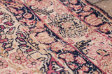 Blanched antique Kerman rug with faded rose and deep navy floral patterns.