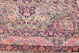 Time-softened rose and navy floral motifs on the blanched Kerman ground.