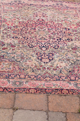 Intricate blanched pink and deep navy floral border of an antique Kerman rug.