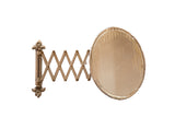 Antique oval beveled glass shaving mirror with fleur de lis mount and aged accordion.
