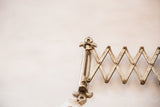 Patina on the antique accordion mirror's fleur de lis hardware and mechanism.