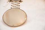 Oval antique shaving mirror showing beveled glass and an aged surface patina.