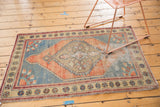 Section of a distressed vintage Oushak rug displaying playful floral border motifs and an abrashed field.