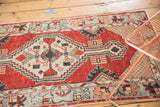 Distressed vintage Oushak runner showing the ivory cross-hatched corner spandrel and cherry red field.