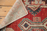 Vintage distressed Oushak rug corner revealing its hand-knotted foundation and red, blue, ivory pattern.