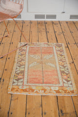 Fringed corner of a distressed Turkish Oushak rug, with bronze, tangerine, and ivory floral patterns.