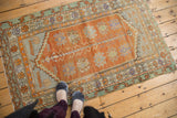 Distressed Oushak rug corner featuring tangerine field, stepped zig-zag spandrel, and floral border.