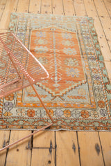 Soft tangerine orange, mint, and mauve floral palmettes on a distressed Oushak rug.