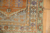 Distressed vintage Oushak rug corner with stepped spandrel, geometric florals, and budded branches.