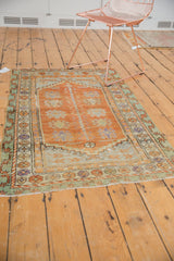Distressed vintage Oushak rug featuring faded tangerine field and mint green floral borders.