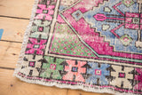 Distressed corner of a Vintage Oushak rug, showing worn pink, pale blue, green primitive patterns.