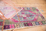 Vibrant pink, blue, and ivory distressed Oushak rug texture with even wear.