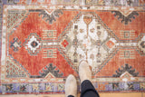 Vintage distressed Oushak runner underfoot, highlighting faded cherry red field and wear.