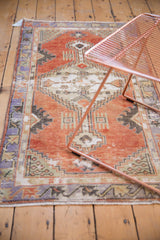 Distressed Oushak runner field in faded cherry red, with visible foundation and ivory spandrels.