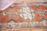 Faded cherry red Oushak runner's distressed field with ivory stepped corner spandrel.