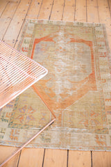 Distressed Oushak rug with worn pile, faded terracotta medallion, and pale blue details.