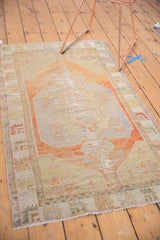 Distressed Oushak rug corner showing asymmetric spandrels, pale terra cotta, and worn texture.