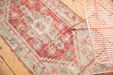 Distressed Oushak runner showcasing faded cherry red floral shrub motifs on ivory and platinum.