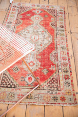 Distressed Oushak rug, faded pomegranate field, antique ivory border, splayed floral cross-sections.