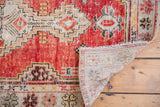 Distressed red and ivory geometric pattern, showing worn pile and hand-knotted reverse.