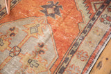 Faded brick red and antique ivory primitive patterns on a distressed Oushak rug.