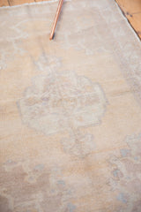 Distressed vintage Oushak rug texture with worn pile, soft ivory, beige, and faded mauve pattern.
