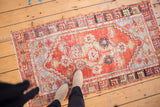 Distressed vintage Oushak rug corner detail with vibrant cherry red, pale blue, and geometric borders.