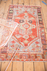 Distressed Oushak rug displaying serrated floral motifs in cherry red, silver, and beige.
