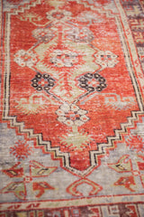 Distressed vintage Oushak rug pile with even wear, showing cherry red field and floral shrub motif.