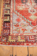 Fringed edge showing cherry red, beige, and chocolate geometric border patterns of the Oushak rug.