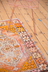 Distressed vintage Oushak rug corner showing worn low pile, visible knot heads, tangerine orange and blush motifs.