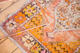 Corner view of the distressed Oushak rug's rich tangerine and saffron tones with unique pile texture.