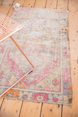 Distressed Oushak rug corner: oversized geometric floral border in pink, purple with visible wear.