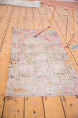 Distressed Oushak rug end with worn texture, pink, purple, ivory tones, and fringe.