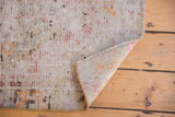 Worn texture and visible foundation of a distressed Oushak rug with patterned reverse.