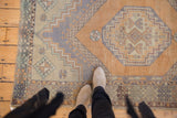 Faded octagonal medallion and hook-and-latch border on a distressed vintage Oushak rug.