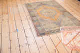 Faded burnt orange octagonal medallion, diamond border, and celadon vine motifs on Oushak rug.