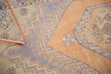 Textured pile of vintage Oushak rug, faded burnt orange and muted blue geometric patterns.