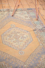 Distressed Oushak rug's octagonal center medallion, diamond border, faded orange and blue tones.